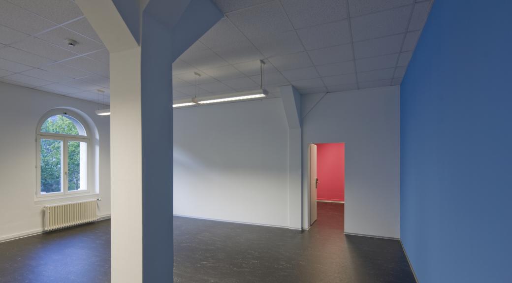 Sitzungszimmer/Musikzimmer mit dunklem Boden und blauer Wand, links die Fenster